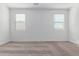Bright bedroom featuring neutral carpet, white walls, and natural light from two large windows at 17081 W Seldon Ln, Waddell, AZ 85355