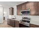 Well-equipped kitchen boasts stainless steel appliances, quartz countertops, and tiled backsplash at 17081 W Seldon Ln, Waddell, AZ 85355