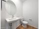 Modern half bathroom features a pedestal sink and a round mirror at 17445 W Via Dona Rd, Surprise, AZ 85387