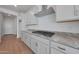 Modern kitchen with stainless steel hood vent and cooktop, granite countertops, and ample cabinet space at 17445 W Via Dona Rd, Surprise, AZ 85387