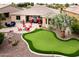 Expansive backyard with a putting green, a cozy fire pit, outdoor seating, and desert landscaping at 20623 N Enchantment Pass, Maricopa, AZ 85138