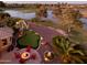 Backyard view showcases the putting green, patio with fire pit, landscaping, and serene water view at 20623 N Enchantment Pass, Maricopa, AZ 85138