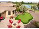 Spacious backyard featuring a putting green, a paved patio with a fire pit, and desert landscaping at 20623 N Enchantment Pass, Maricopa, AZ 85138