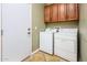 Well-lit laundry room with washer, dryer, and overhead cabinet storage at 20623 N Enchantment Pass, Maricopa, AZ 85138