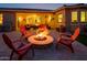 Picturesque outdoor patio with a stone fire pit, comfortable seating, and beautiful lighting for evening gatherings and enjoyment at 20623 N Enchantment Pass, Maricopa, AZ 85138