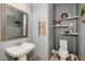 Stylish powder room featuring a pedestal sink, neutral gray walls, and decorative shelving for a modern and functional space at 20623 N Enchantment Pass, Maricopa, AZ 85138