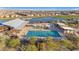 Aerial view of a community pool and splash pad with lounge chairs, a lake, and a park under a clear blue sky at 25582 S 224Th Way, Queen Creek, AZ 85142