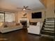 Bright living room with a fireplace, ceiling fan, large TV, and access to the staircase at 3030 N Hayden Rd # 28, Scottsdale, AZ 85251