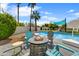 Relaxing pool area with cozy fire pit, chairs, lush landscaping, and palm trees for endless summer fun at 6525 N 83Rd St, Scottsdale, AZ 85250