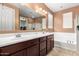 Bathroom featuring double sinks, large mirror, soaking tub, and shower with glass doors at 7975 W Andrea Dr, Peoria, AZ 85383