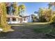 Expansive grassy backyard with a white house, mature trees and a covered patio at 8002 N 5Th Ave, Phoenix, AZ 85021