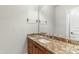 Bathroom vanity featuring granite countertop, wood cabinets, a sink and large mirror, and gold fixtures at 9869 E Davenport Dr, Scottsdale, AZ 85260