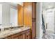 Bathroom vanity featuring wood cabinets, granite counters, mirror and a view to the bathtub/shower at 9869 E Davenport Dr, Scottsdale, AZ 85260