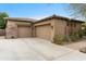 Spacious three-car garage with stone accents and a concrete driveway at 9869 E Davenport Dr, Scottsdale, AZ 85260