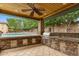 Inviting outdoor kitchen and bar area under a covered patio, overlooking a pool and lush backyard at 9869 E Davenport Dr, Scottsdale, AZ 85260