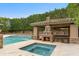 Relaxing backyard featuring a pool, hot tub, outdoor bar with fireplace, creating an ideal space for entertaining guests at 9869 E Davenport Dr, Scottsdale, AZ 85260