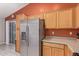Kitchen featuring stainless steel appliances, light wood cabinetry, and a refrigerator with a water dispenser at 12630 W Aster Dr, El Mirage, AZ 85335