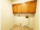 Small laundry room with tile flooring and upper wood cabinets at 1606 E Cactus Wren Dr, Phoenix, AZ 85020