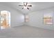 Bright main bedroom featuring plush carpet, ceiling fan, and an ensuite bathroom with a walk-in shower at 16671 W Mckinley St, Goodyear, AZ 85338
