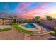 Backyard with pool, patio, and landscaping under a vibrant sky at dusk at 16671 W Mckinley St, Goodyear, AZ 85338