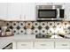 Modern kitchen with white cabinets, quartz countertops, and stylish patterned backsplash at 17614 N 56Th Way, Scottsdale, AZ 85254