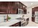 Close up of chef's kitchen featuring stainless steel stove and range hood, and white countertops at 17938 W Cedarwood Ln, Goodyear, AZ 85338