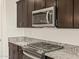 Gleaming stainless steel microwave and cooktop highlighted by granite countertops and dark-wood cabinetry at 24612 W Grenadine Rd, Buckeye, AZ 85326