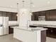 Modern kitchen featuring dark wood cabinets, stainless steel appliances, and a spacious island with granite countertops at 24612 W Grenadine Rd, Buckeye, AZ 85326
