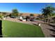 Landscaped backyard with lush artificial turf, gravel, blooming plants, and inviting fire pit area at 26947 W Adam Ave, Buckeye, AZ 85396