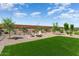 Backyard showcasing lush turf, desert landscaping, and a stylish fire pit area at 26947 W Adam Ave, Buckeye, AZ 85396