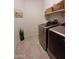 Well-organized laundry room with modern washer and dryer set, storage shelves, and tiled flooring at 26947 W Adam Ave, Buckeye, AZ 85396