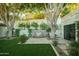 Private backyard featuring lush green grass, mature trees, and a stone water feature at 3140 E Claremont Ave, Phoenix, AZ 85016