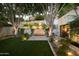 Backyard with a stone water feature, mature trees, and lush grass at 3140 E Claremont Ave, Phoenix, AZ 85016