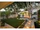 Serene backyard with lush greenery, mature trees, ambient lighting, and stone pavers at 3140 E Claremont Ave, Phoenix, AZ 85016