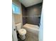 Bathroom featuring gray tiled walls, tub, shower, and a window at 3739 W Mission Ln, Phoenix, AZ 85051