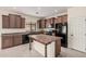Kitchen boasts dark cabinetry, a center island, black appliances, and sleek tile flooring at 5108 N 191St Dr, Litchfield Park, AZ 85340