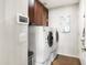 Functional laundry room with white washer and dryer, dark cabinets, and a bright interior at 9654 E Pantera Ave, Mesa, AZ 85212