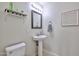 Functional half bathroom with a pedestal sink, decorative mirror and a low-flow toilet at 10022 W Luxton Ln, Tolleson, AZ 85353