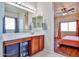 Bright bathroom features a vanity with storage and a large mirror, leading to a bedroom with warm lighting at 10022 W Luxton Ln, Tolleson, AZ 85353