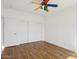 Bedroom with hardwood floors and a large closet with sleek white sliding doors. A colorful fan adds character at 11097 Quinn Dr, Goodyear, AZ 85338