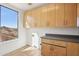 Functional laundry room equipped with wooden cabinets, countertops, and a view of the desert landscape at 11097 Quinn Dr, Goodyear, AZ 85338