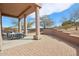 Relaxing covered patio with brick pavers and a comfortable seating area overlooking a professionally landscaped desert yard at 11097 Quinn Dr, Goodyear, AZ 85338