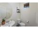 Powder room featuring a pedestal sink, round mirror, and toilet, accented with decorative shelving at 12018 W Taylor St, Avondale, AZ 85323