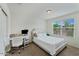 Bright bedroom featuring a white upholstered bed, desk, and natural light from a window at 12018 W Taylor St, Avondale, AZ 85323
