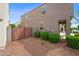 Exterior view of a two-story home featuring a wooden gate, desert landscaping, and a stucco facade at 12018 W Taylor St, Avondale, AZ 85323