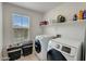 Bright laundry room with front-load washer and dryer, a window, and built-in shelving for storage at 12018 W Taylor St, Avondale, AZ 85323
