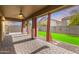 Inviting back patio featuring red curtains, brick pavers, and an artificial grass yard at 12221 W Locust Ln, Avondale, AZ 85323