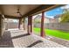 Inviting back patio featuring red curtains, brick pavers, and an artificial grass yard at 12221 W Locust Ln, Avondale, AZ 85323