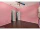 Pink painted bedroom featuring wood-look floors, closet, ceiling fan at 12221 W Locust Ln, Avondale, AZ 85323