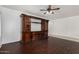 Living room with hardwood floors, custom entertainment center, and ceiling fan at 12221 W Locust Ln, Avondale, AZ 85323